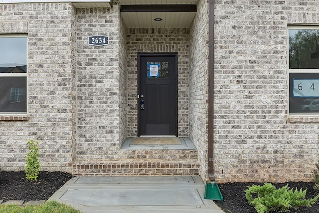 doorway to property featuring brick siding