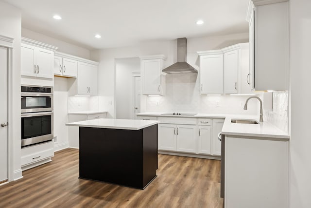 kitchen featuring a sink, double oven, black electric stovetop, dark wood finished floors, and wall chimney range hood