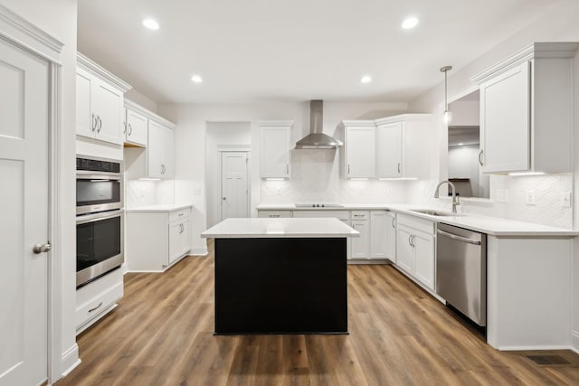 kitchen with wall chimney exhaust hood, a center island, a sink, appliances with stainless steel finishes, and wood finished floors