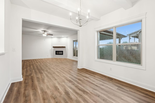 unfurnished living room featuring baseboards, wood finished floors, a glass covered fireplace, and beamed ceiling