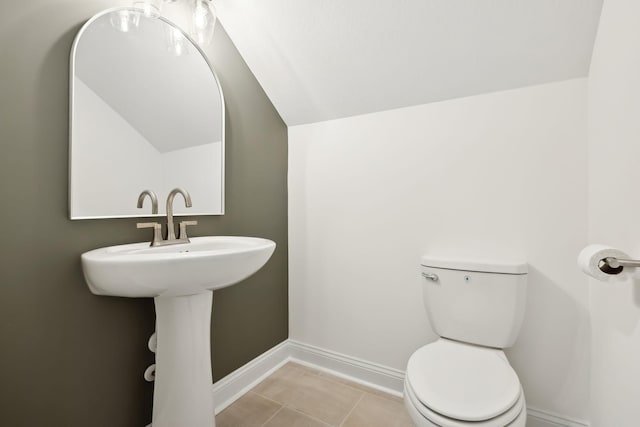 bathroom with baseboards, lofted ceiling, toilet, and tile patterned flooring