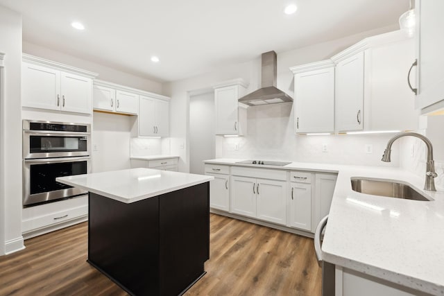 kitchen with dark wood-style flooring, black electric stovetop, double oven, a sink, and wall chimney range hood