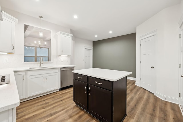 kitchen with light countertops, a sink, stainless steel dishwasher, white cabinets, and light wood-style floors