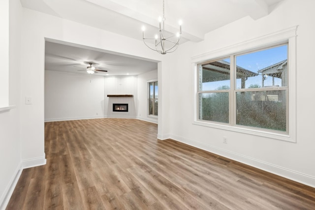 unfurnished living room featuring baseboards, beamed ceiling, wood finished floors, and a glass covered fireplace