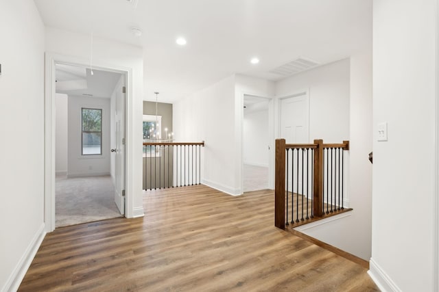 corridor featuring an upstairs landing, visible vents, attic access, and wood finished floors