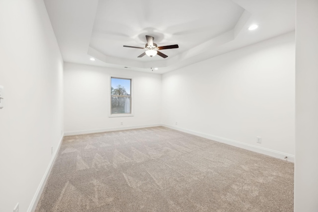 unfurnished room with baseboards, recessed lighting, a ceiling fan, a tray ceiling, and light colored carpet