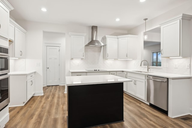 kitchen featuring a sink, wall chimney range hood, wood finished floors, and dishwasher