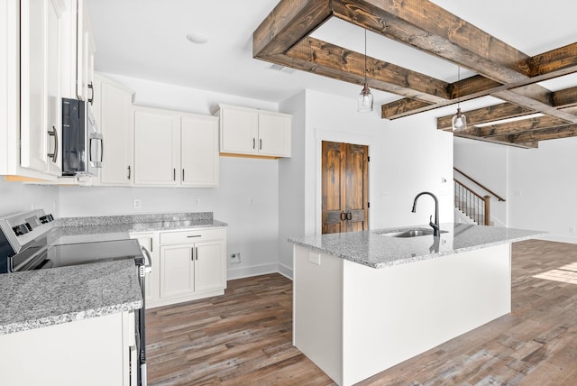 kitchen featuring stove, a center island with sink, white cabinetry, and sink