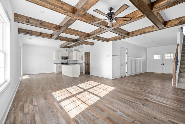 unfurnished living room featuring beamed ceiling, light hardwood / wood-style floors, ceiling fan, and coffered ceiling