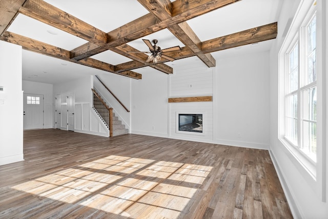 unfurnished living room featuring beamed ceiling, light wood-type flooring, and coffered ceiling