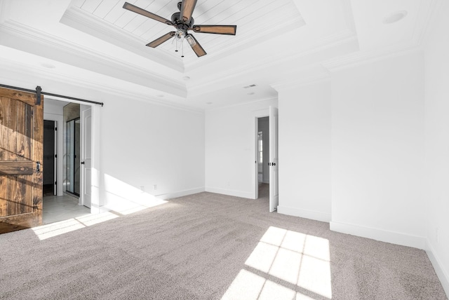 carpeted spare room featuring a barn door, a raised ceiling, ceiling fan, and crown molding