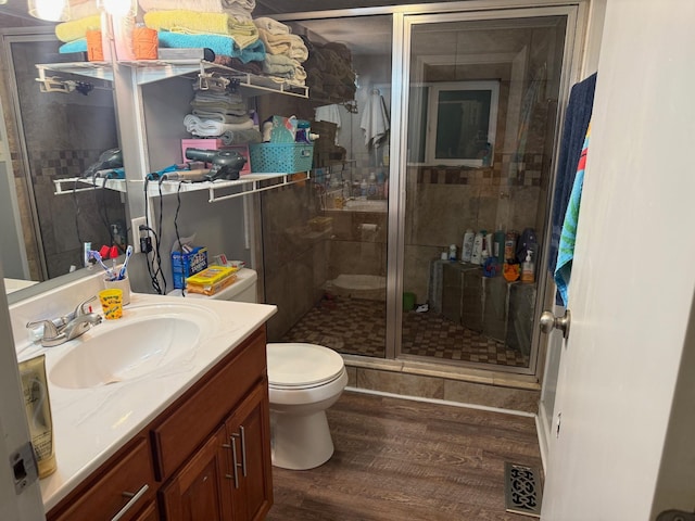 bathroom with a shower with shower door, toilet, wood-type flooring, and vanity