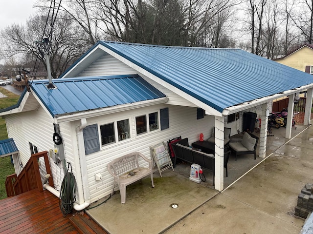 exterior space featuring a deck, metal roof, an outdoor hangout area, a carport, and a patio area