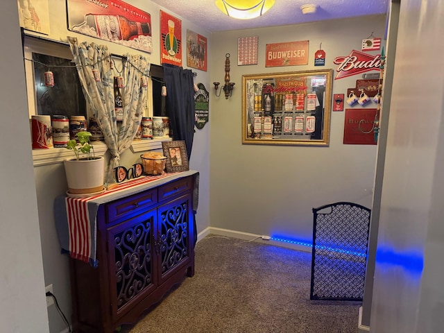 hallway featuring a textured ceiling and dark carpet