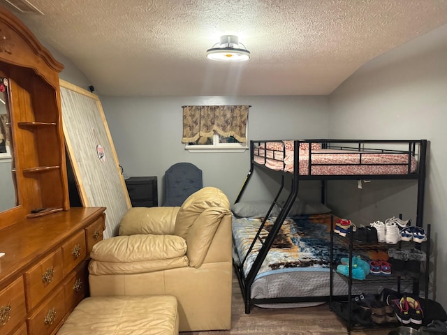 bedroom featuring a textured ceiling, hardwood / wood-style flooring, and lofted ceiling