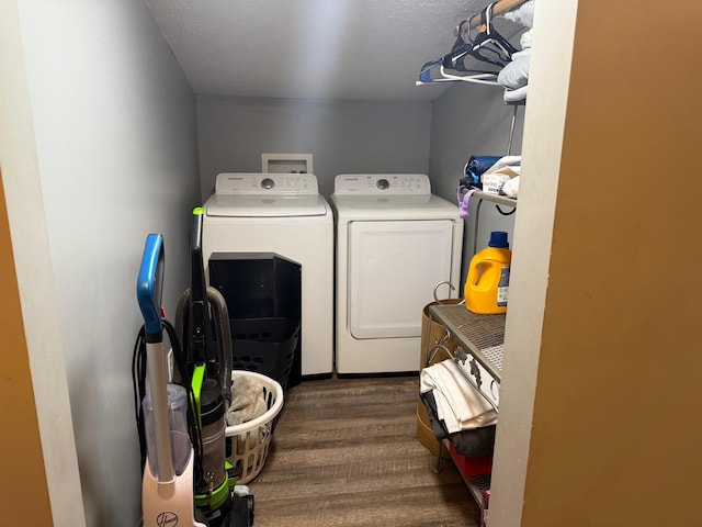 laundry room featuring washing machine and clothes dryer, a textured ceiling, and dark hardwood / wood-style floors