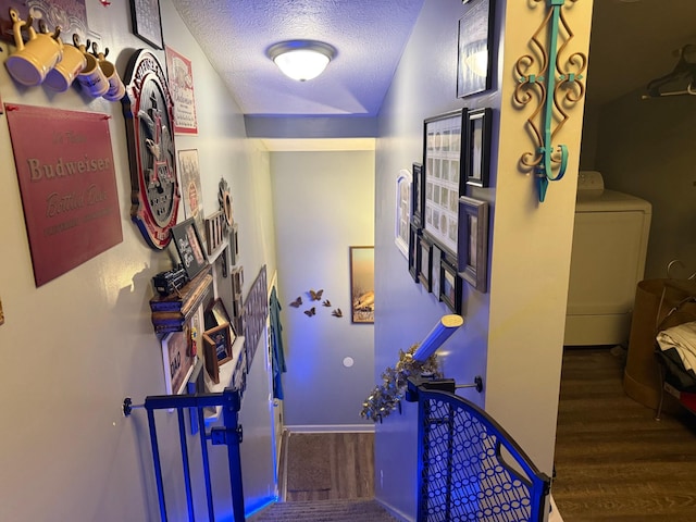 corridor with a textured ceiling, wood finished floors, and washer / dryer