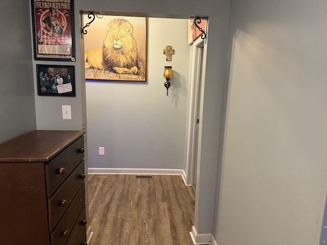 hallway with dark wood-type flooring, visible vents, and baseboards