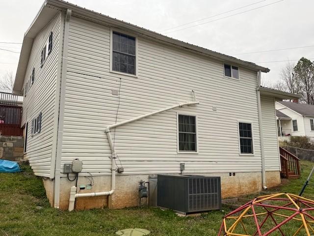 rear view of house with central air condition unit, crawl space, and a lawn