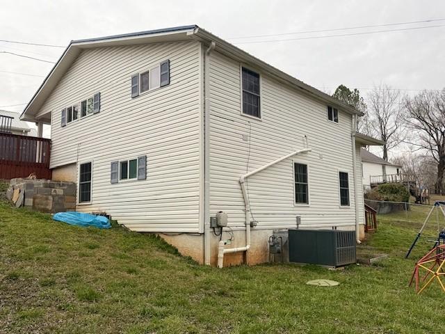 rear view of property with a yard, cooling unit, and fence