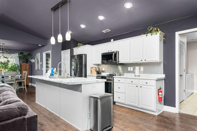 kitchen featuring white cabinets, appliances with stainless steel finishes, dark hardwood / wood-style flooring, and a kitchen island with sink