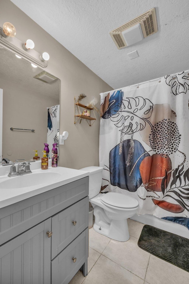 bathroom with tile patterned flooring, vanity, a textured ceiling, and toilet