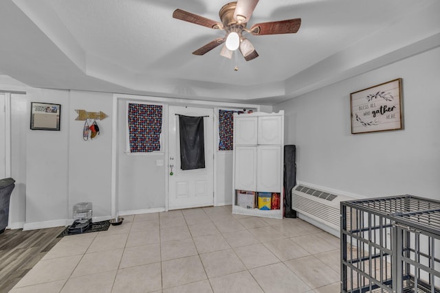 bedroom featuring a tray ceiling, ceiling fan, light tile patterned floors, and a textured ceiling