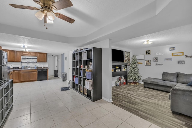 living room with ceiling fan, light hardwood / wood-style flooring, a textured ceiling, and sink