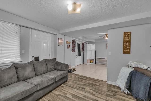 living room featuring ceiling fan, wood-type flooring, a textured ceiling, and a wall unit AC