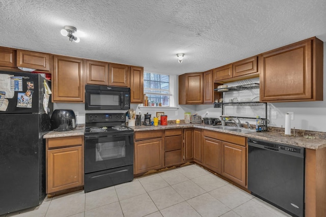 kitchen featuring black appliances, light tile patterned floors, sink, and a textured ceiling