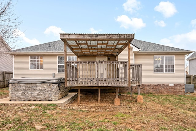 rear view of property with a wooden deck, a hot tub, a lawn, and central air condition unit