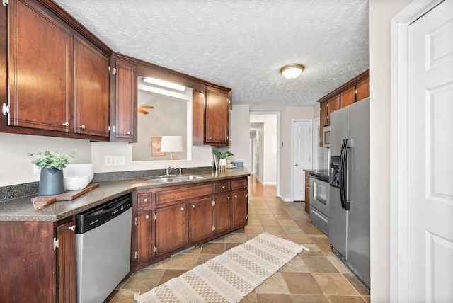 kitchen with sink, a textured ceiling, and appliances with stainless steel finishes