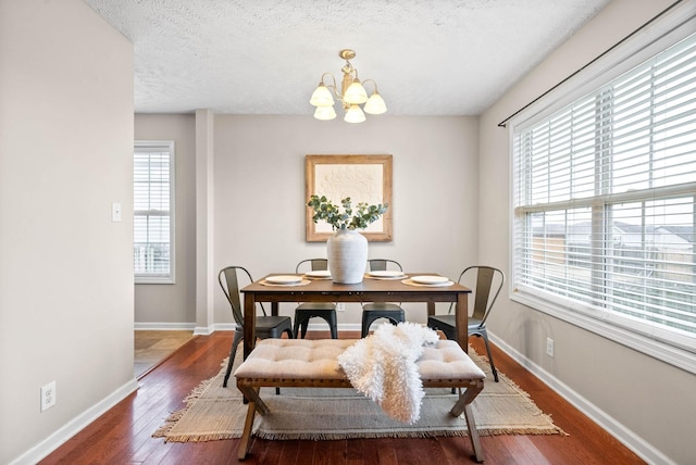 dining area with dark hardwood / wood-style floors, a textured ceiling, and a notable chandelier