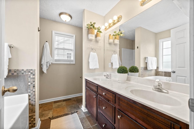 bathroom with vanity, a tub, and a textured ceiling