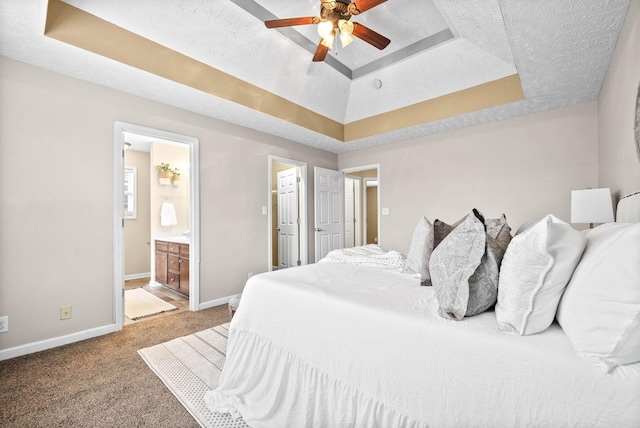 bedroom featuring ceiling fan, connected bathroom, a textured ceiling, light carpet, and a raised ceiling