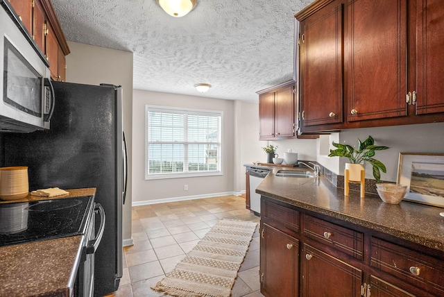 kitchen with appliances with stainless steel finishes, sink, dark stone counters, and light tile patterned floors