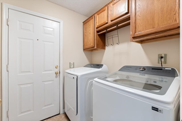 laundry room with cabinets, washer and clothes dryer, and a textured ceiling