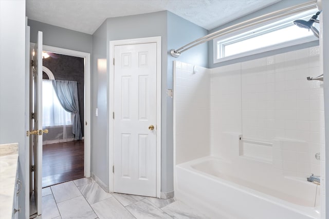 bathroom with shower / bathing tub combination, vanity, and a textured ceiling