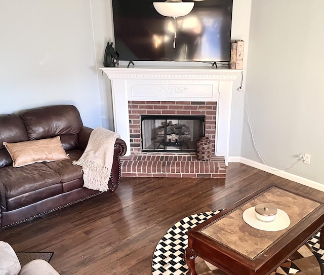 living room featuring a brick fireplace and dark wood-type flooring