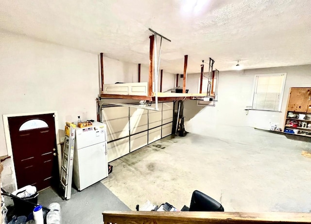 basement with a textured ceiling and white fridge