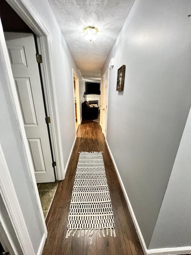 hallway featuring dark hardwood / wood-style floors and a textured ceiling