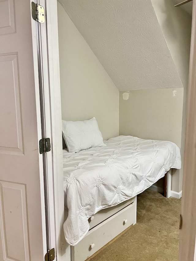 carpeted bedroom featuring vaulted ceiling and a textured ceiling