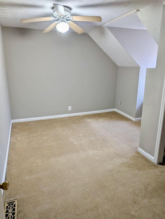 bonus room with vaulted ceiling, light carpet, a textured ceiling, and ceiling fan