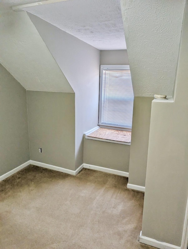 bonus room featuring vaulted ceiling, light colored carpet, and a textured ceiling