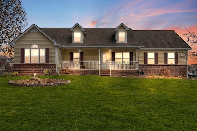 cape cod-style house with a yard and a porch