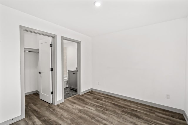 unfurnished bedroom with dark hardwood / wood-style flooring, connected bathroom, and a closet