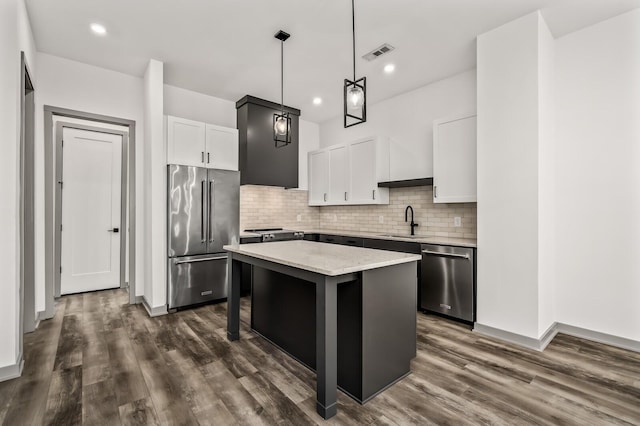 kitchen with pendant lighting, stainless steel appliances, a kitchen island, and white cabinetry