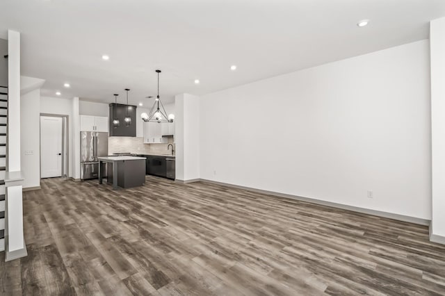 unfurnished living room with dark hardwood / wood-style flooring, sink, and an inviting chandelier