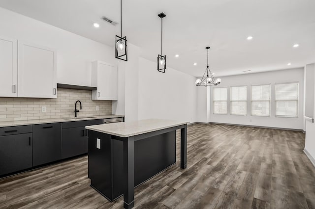 kitchen featuring sink, hanging light fixtures, a notable chandelier, a kitchen island, and white cabinetry