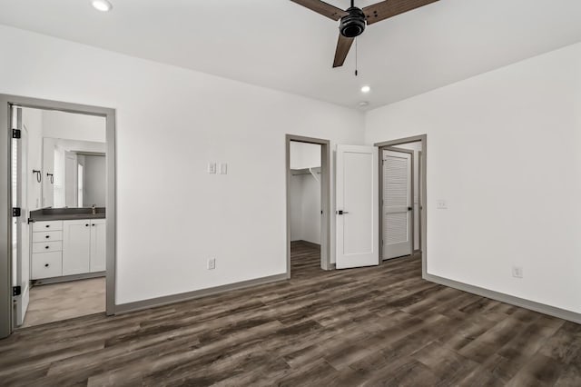 unfurnished bedroom featuring ensuite bath, ceiling fan, a spacious closet, and dark hardwood / wood-style floors